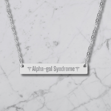 Load image into Gallery viewer, A silver bar necklace with the words 'Alpha-gal Syndrome' engraved in the center, flanked by caduceus symbols, displayed on a white marble background.
