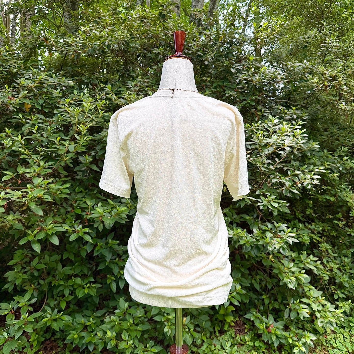 Mannequin wearing a white shirt with a forest background